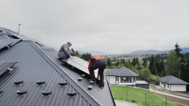 技术人员在房顶上建造光伏太阳能模块站 戴着头盔的男性电工在室外安装太阳能电池板系统 替代能源和可再生能源的概念 空中景观 — 图库视频影像