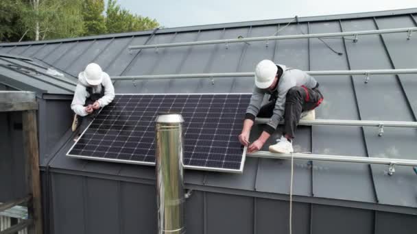 在房顶上安装光电太阳能电池板的技师 头盔上的男性工程师使用六角钥匙建造太阳能组件系统 可再生能源的替代概念 — 图库视频影像