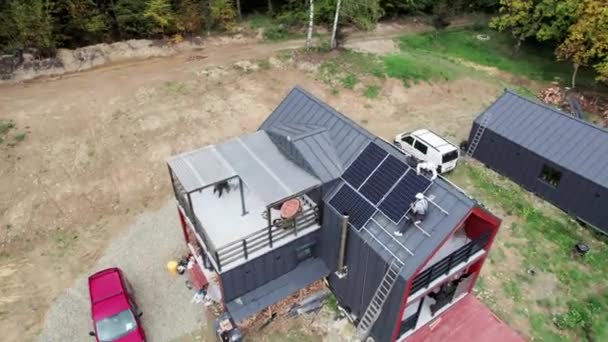屋根の上に太陽電池モジュールステーションを構築する技術者 太陽電池パネルシステムを屋外に設置ヘルメットの男性電気技師 代替エネルギーと再生可能エネルギーの概念 空中風景 — ストック動画
