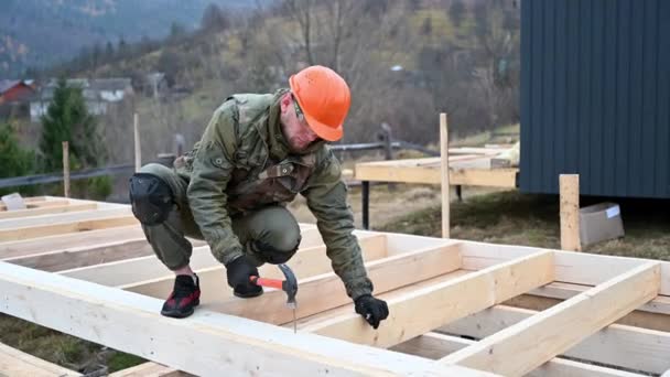 工人在桩基础上建造木制框架房屋 木匠用铁锤把钉子锤入木架 木匠概念 — 图库视频影像