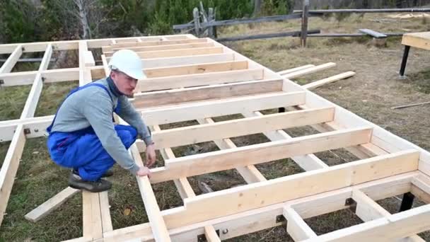 Arbeiter Bauen Holzrahmenhaus Auf Pfahlfundament Tischler Beim Messen Von Holzbohlen — Stockvideo