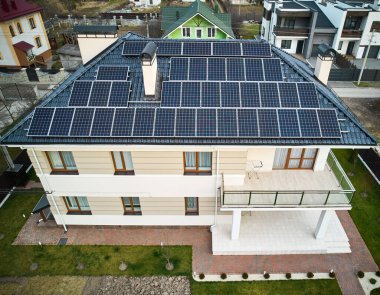 Aerial view of two-storey house with solar panel modules for generating electricity through photovoltaic effect. New home with ecological renewable energy source on roof. Solar power system concept.