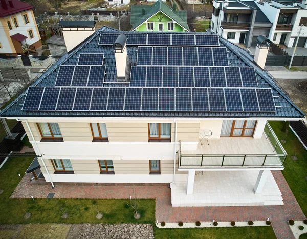 stock image Aerial view of two-storey house with solar panel modules for generating electricity through photovoltaic effect. New home with ecological renewable energy source on roof. Solar power system concept.