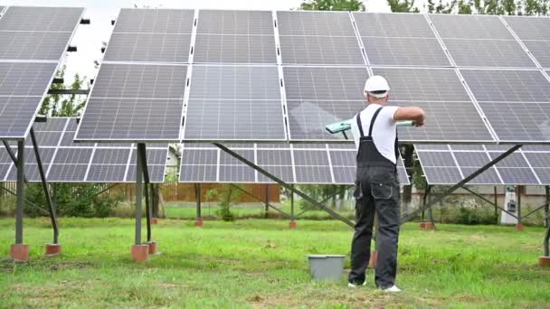 技师用拖把清洁太阳能光伏面板 对穿着工作服和头盔的男人照顾光电池的后视镜 替代能源创新概念 — 图库视频影像