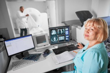 Tıbbi bilgisayarlı tomografi ya da MRI tarayıcısı. Bilgisayarda çalışan kadın hemşire portresi, MRI yapıyor. Mavi üniformalı bir kadın. Tıp ve hastane kavramı.