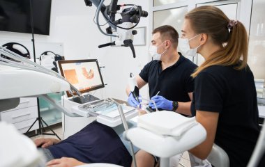 Dentist scanning patients teeth with modern machine for intraoral scanning. Digital print of patients teeth is on big screen. Modern high precision technologies. Concept of modern dentistry