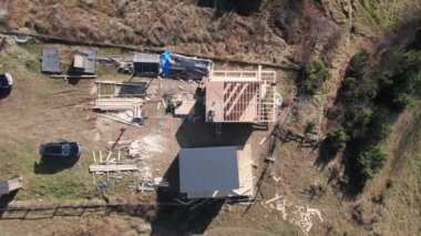 Top view man laying on rooftop of building on construction site in white helmet. Male worker building wooden frame house. Drone view