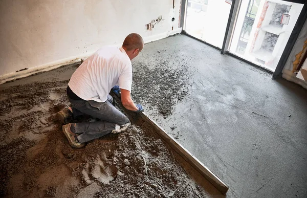 Άνδρας Οικοδόμος Χρησιμοποιώντας Ράγες Ενώ Screeding Πάτωμα Στο Σαλόνι Άντρας — Φωτογραφία Αρχείου