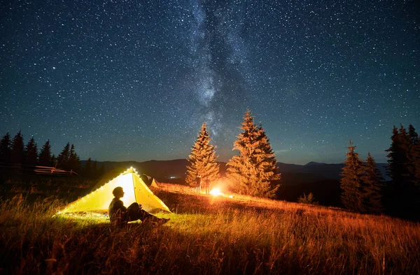 산에서 야영하는 야영지 근처에 쉬면서 화재를 감상하는 관광객 실루엣 은하수와 — 스톡 사진
