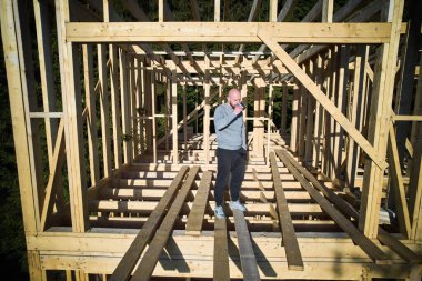 Müşteri ormanın yakınına ahşap çerçeve yaptırıyor, bir fincan kahve içiyor. Arkasındaki konsept modern ve çevre dostu yapı..