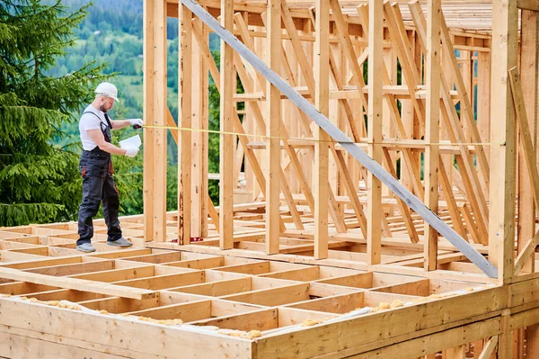Stolarz Buduje Drewniany Szkieletowy Dom Człowiek Mierzy Odległości Pomocą Miarki — Zdjęcie stockowe