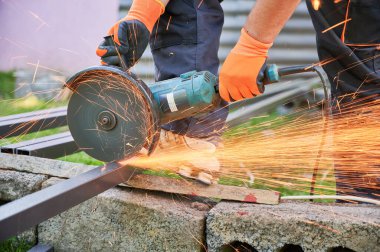 Öğütücüyle metal direği kesen bir işçi. Öğütme makinesi. Kısmi insan sureti. Yakın plan. Metal işçiliğinde kıvılcımlar