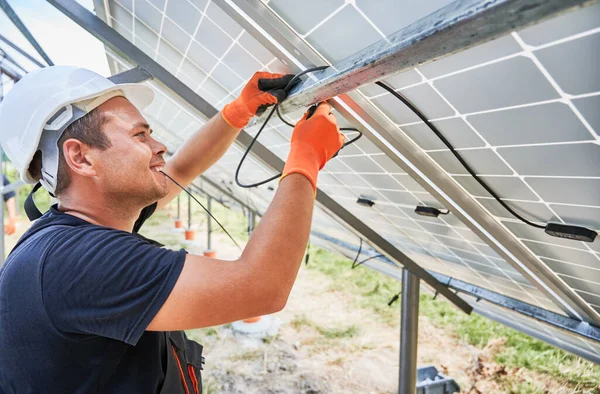 将工人的太阳能电池板接上电线 男子在室外安装光电太阳能电池板系统 戴安全帽和工作手套 可再生能源的概念 — 图库照片