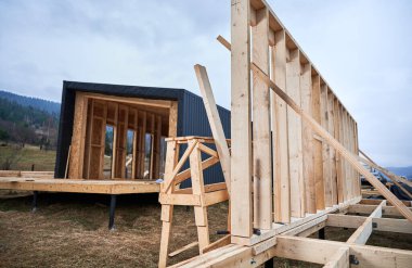 Wooden frame house on pile foundation in the Scandinavian style barnhouse under construction.