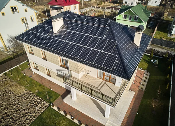 Home residence with solar panel system for generating electricity through photovoltaic effect. Aerial view of two-storey house with solar modules on roof. Ecological renewable energy sources concept.