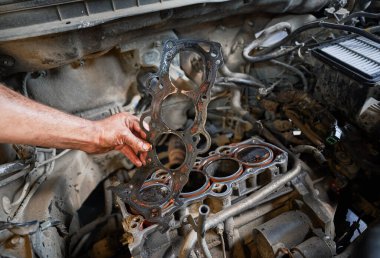 Close up of worker, repairman, mechanic fixing, repairing car. Hardworking man holding dirty steel detail, equipment, working in garage. Concept of repairing, fixing car.