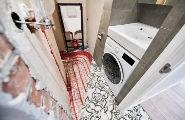 Tadilattan önce ve sonra lavabo karşılaştırması. Yeraltı ısıtma boruları ve yeni yenilenmiş çamaşır makinesi olan eski apartman tuvaleti..