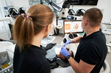 Dentist scanning patients teeth with modern machine for intraoral scanning. Digital print of patients teeth is on big screen. Modern high precision technologies. Concept of modern dentistry