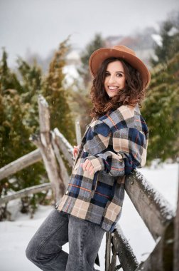 Curly young woman resting in the mountains. Portrait of happy female tourist enjoying winter holidays.