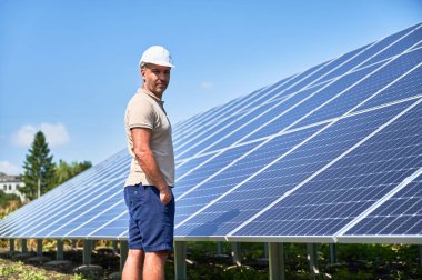 Profesyonel işçi PV güneş panellerini kontrol ediyor. Modern enerji kaynağının yanında duran yetişkin adam. Yeşil enerji kaynakları kavramı.