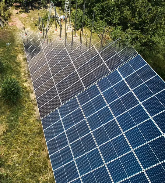 Installing solar panels system in field at sunny daytime. Concept of renewable ecological energy. Modern technology and innovation. Idea of environment safety. Aerial view
