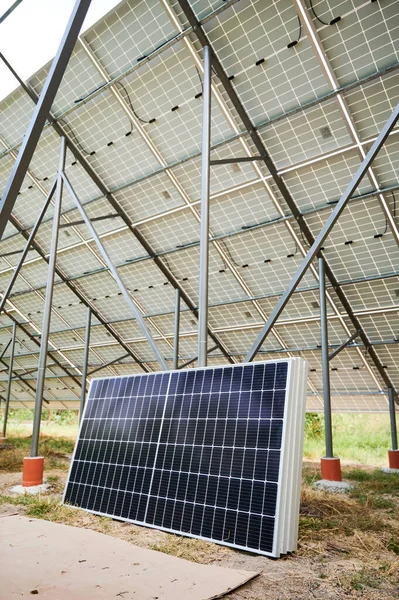 Set of solar panels under solar energy system on metal beams in field. Renewable ecological energy. Photo-voltaic collection of modules. Array - system of photo-voltaic panels. Environment safety.