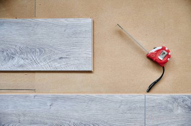 Bant ölçüsü ve ahşap döşeme döşemeleri ev yenileme, inşaat işleri ve iç tasarım için. Döşeme için bant cetvel aracı ve ahşap desenli kaplamalar ölçülüyor.