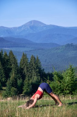 Dağlarda sabah egzersizi yapan bir kadın. Esnek, genç bir kadın yoga yapıyor. Sıska bir kadın başının üstünde duruyor, esniyor, meditasyon yapıyor spor giysiler giyiyor, seyahat ediyor. Sağlıklı yaşam kavramı.