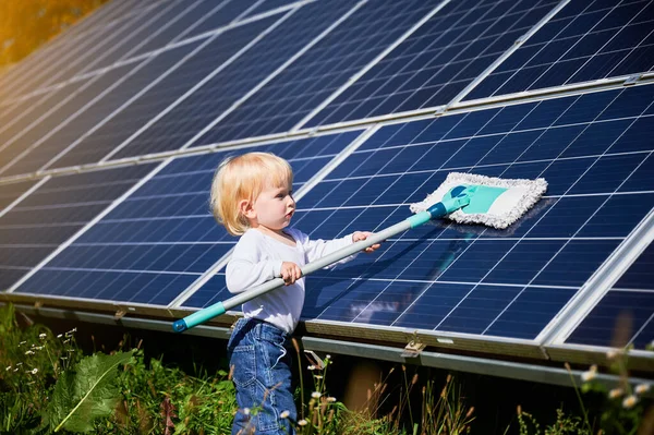 Small boy learning how to care about solar panels. Young kid cleaning new solar battery at warm sunny day. Concept of young generation and alternative energy.