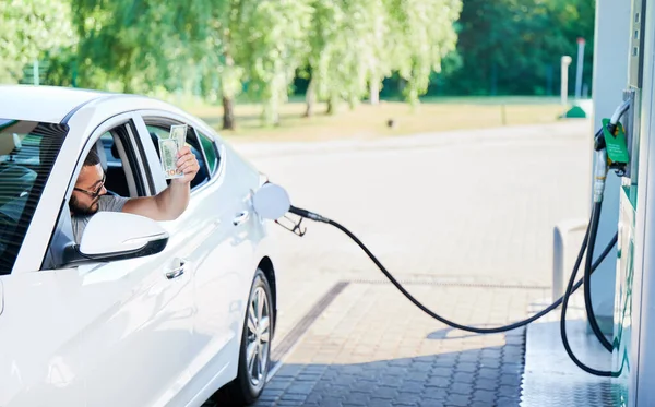 Stock image Confident man paying for refueling his luxury car. Man waiting for gas station operator take money for filling cat tank. Young male giving money through window.