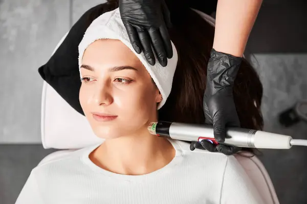 Doktor Güzellik Uzmanı hasta için yenilenme prosedürü yaparken radyoterapi cihazı kullanıyor. Güzellik salonunda radyoterapi gören bir kadın. Donanım kozmetoloji kavramı.