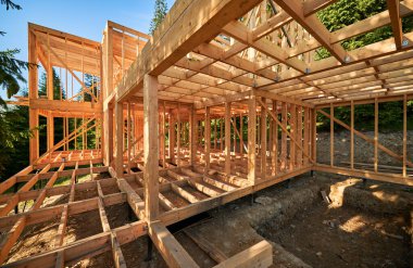 Residential wooden frame house under construction near a forest. Beginning of new construction of cozy house or cottage. The concept of modern ecological construction and architecture. clipart