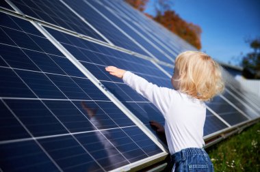 Meraklı çocuk güneş panelinin nasıl çalıştığıyla ilgileniyor. Küçük çocuk koyu mavi güneş piline bakıyor. Genç nesil ve alternatif enerji kavramı.