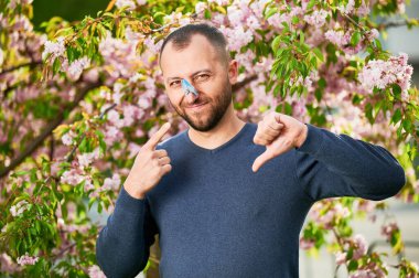 İlkbaharda alerji yüzünden acı çeken bir adam. Sakallı ve burnuna toka takılmış bir adam. Burun tıkanıklığı nedeniyle nefes alamaması sembolik bir jest..
