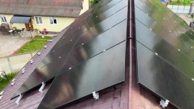 Modern evin çatısındaki güneş fotovoltaik panel sistemi. Banliyö evinin eğimli çatısına güneş pilleri yerleştirildi. Alternatif ve yenilenebilir enerji üretimi kavramı.