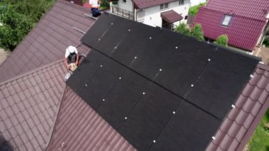 İşçiler evin çatısına güneş paneli inşa ediyorlar. Dışarıda fotovoltaik güneş modülü kuran kask takan iki adam. Alternatif, yeşil ve yenilenebilir enerji üretimi kavramı.