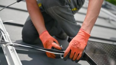İşçi evin çatısına güneş panelleri kuruyor. Elektrikçinin kabloları özel bir kravatla güvence altına aldığına dair yakın görüş. Alternatif ve yenilenebilir enerji kavramı.