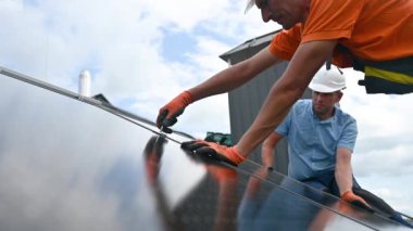 İşçiler evin çatısına fotovoltaik güneş paneli inşa ediyorlar. Güneş modülünü takan eldivenli teknisyenleri kapatın. Dışarıdaki hex anahtarının yardımıyla. Yenilenebilir enerji üretimi kavramı.
