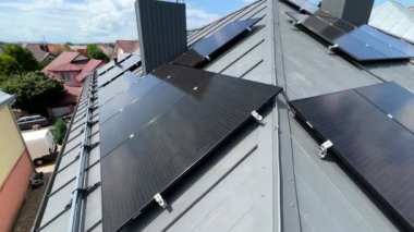 Çatıda fotovoltaik etkiyle elektrik üretmek için güneş panelleri olan bir ev. Çatıda güneş enerjisi sistemi olan bir ev. Alternatif enerji kavramı, özerklik, güç sürdürülebilir kaynaklar.