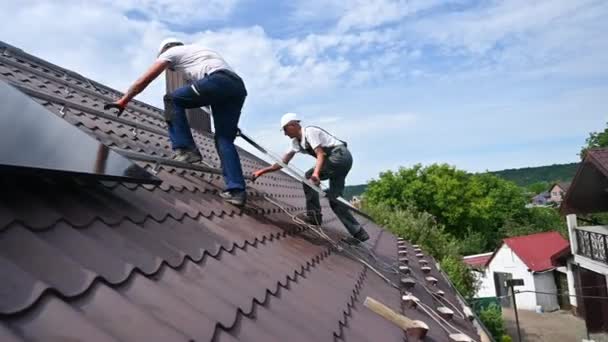 Napelemes Rendszert Építő Munkások Ház Tetején Két Bukósisakos Férfi Fotovoltaikus — Stock videók