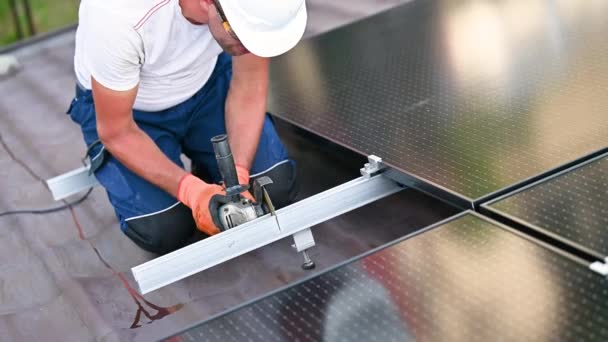 家の屋根に太陽光発電の太陽電池パネル システムを取付けるか または維持する労働者 パネルの土台構造の金属部分の粉砕を使用して技術者を閉めて下さい コンセプト 再生可能エネルギー — ストック動画