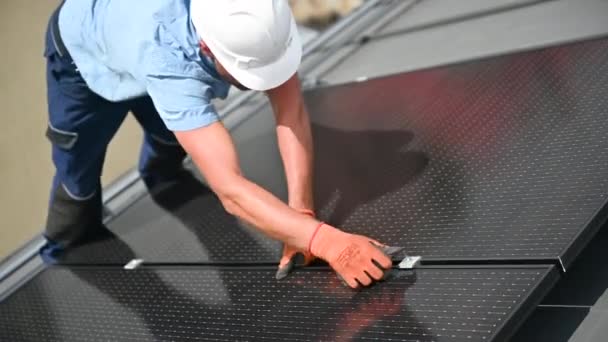 家の屋上に太陽光発電の太陽電池パネル システムを造る労働者 屋外の六角キーの助けを借りて太陽モジュールを取付ける手袋のマン エンジニア 代替エネルギー 再生可能エネルギーのコンセプト — ストック動画