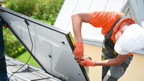 太陽光発電による発電のための家の屋上にソーラーパネルシステムを構築する労働者 正確な取付けのための土台装置を測定するために定規を使用する人 — ストック動画