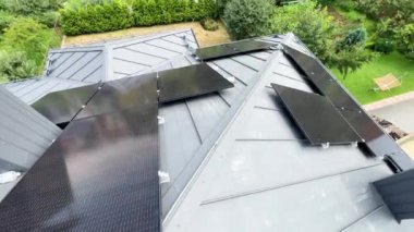 Çatıda fotovoltaik etkiyle elektrik üretmek için güneş panelleri olan bir ev. Çatıda güneş enerjisi sistemi olan bir ev. Alternatif enerji kavramı, özerklik, güç sürdürülebilir kaynaklar.