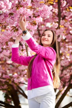 Alerjisi olan bir kadın, bahardaki sezonluk alerjiden zevk alıyor. Baharda çiçek açan sakura ağacının önünde gülümseyen güzel bir kadının portresi. Bahar alerjisi konsepti.