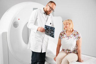 Tıbbi bilgisayarlı tomografi ya da MRI tarayıcısı. Hasta MR çekiyor, doktor nezarette ve sonuçları açıklıyor. Kanepede oturan kadın. Tıp ve sağlık hizmetleri kavramı.