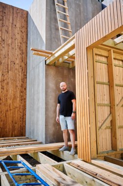 Mimar, ormanın yakınındaki ahşap çerçeveli evin şantiyesinde. Arkasındaki konsept modern ve çevre dostu yapı..