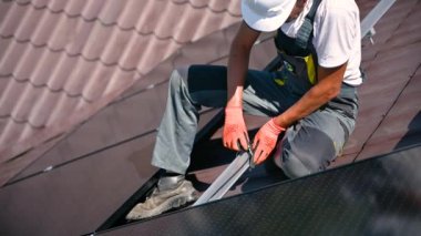 İşçi evin çatısına güneş panelleri kuruyor. Elektrikçinin kabloları özel bir kravatla güvence altına aldığına dair yakın görüş. Alternatif ve yenilenebilir enerji kavramı.