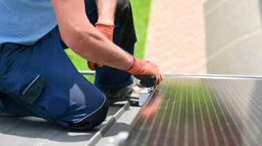 Evin çatısında fotovoltaik güneş paneli inşa eden bir işçi. Eldiven takan insan mühendislerine yakın çekim yapın. Güneş modülü takın. Dışarıdaki hex anahtarının yardımıyla. Alternatif enerji üretimi kavramı.