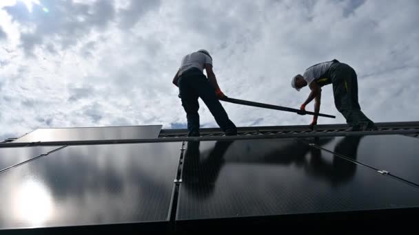 Рабочие Строят Солнечную Панель Крыше Дома Двое Монтажников Шлемах Несут — стоковое видео